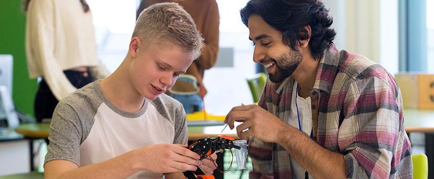 A man helping a younger student on a project